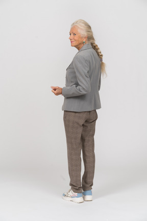 一位身穿灰色夹克的老妇人展示拳头的后视图