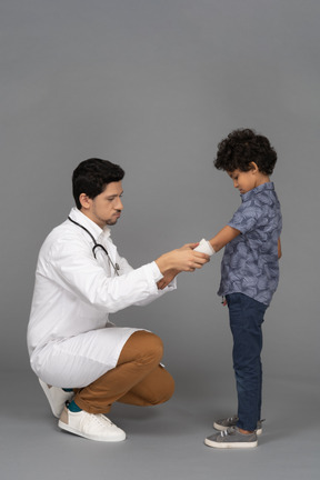 Médico enfaixando a mão de uma criança