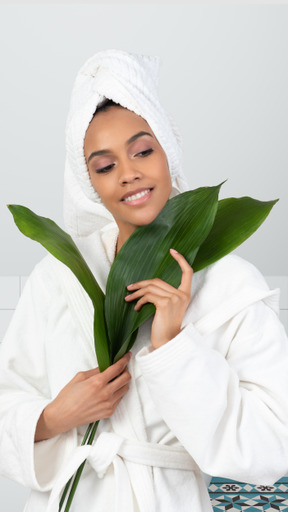 A young woman in a bathrobe holding a green leaf