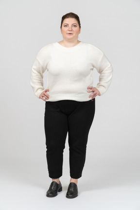 엉덩이에 손으로 서있는 흰색 스웨터에 통통한 여자