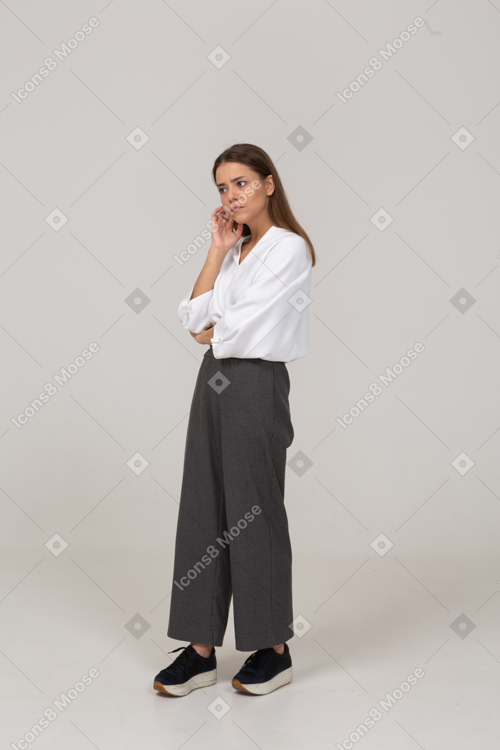 Vista di tre quarti di una giovane donna premurosa in abiti da ufficio che tocca il viso