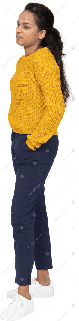 Vista laterale di una ragazza in abiti casual in posa con le mani in tasca