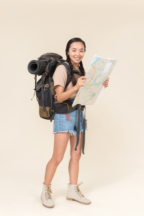 Joven excursionista asiática sosteniendo un mapa parece feliz