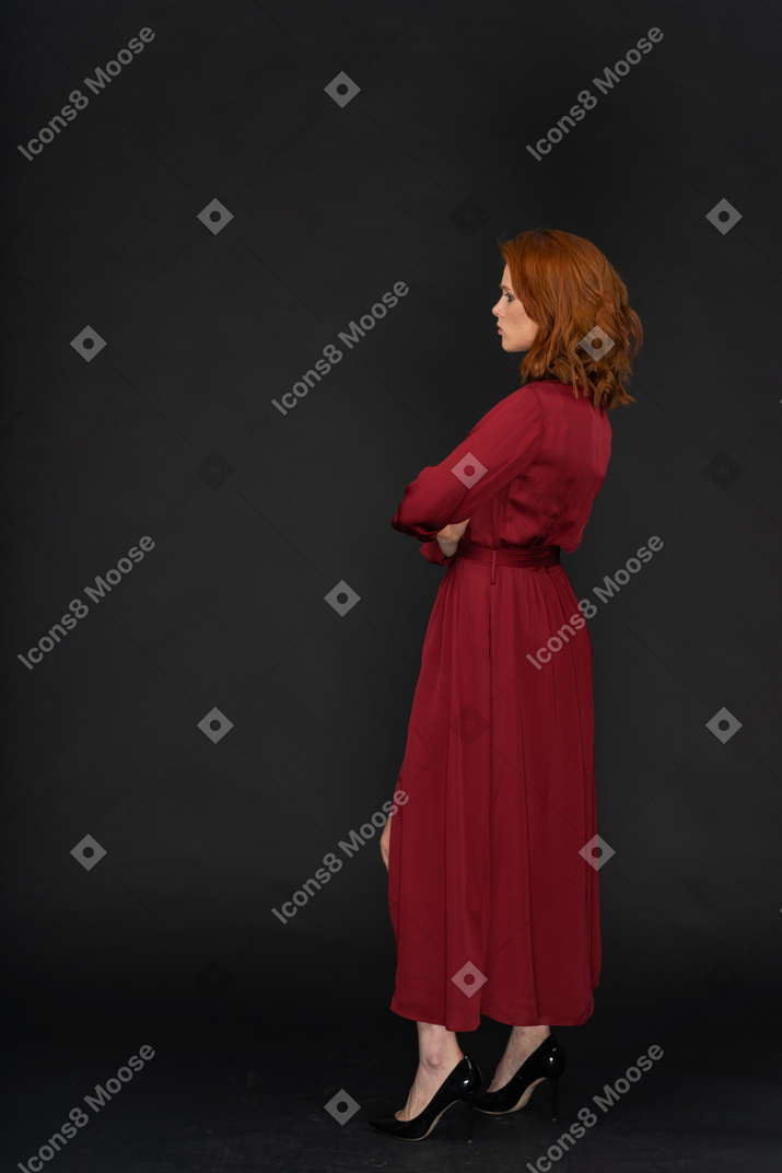 A side view of the young beautiful woman dressed in red and holding her hands on the chest