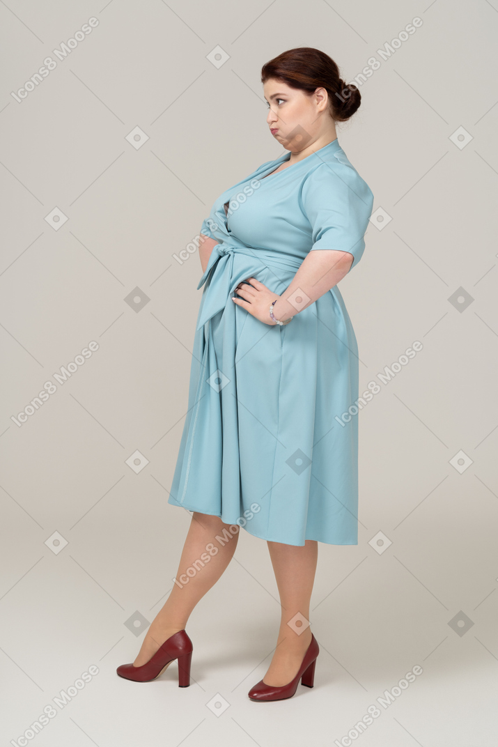 Vista lateral, de, un, mujer, en, vestido azul, posar, con, manos caderas