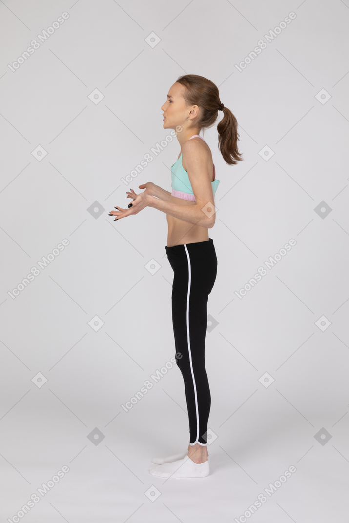 Side view of a teen girl in sportswear gesticulating and questioning