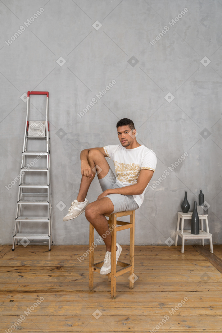 Young man sitting on chair with arm on his knee