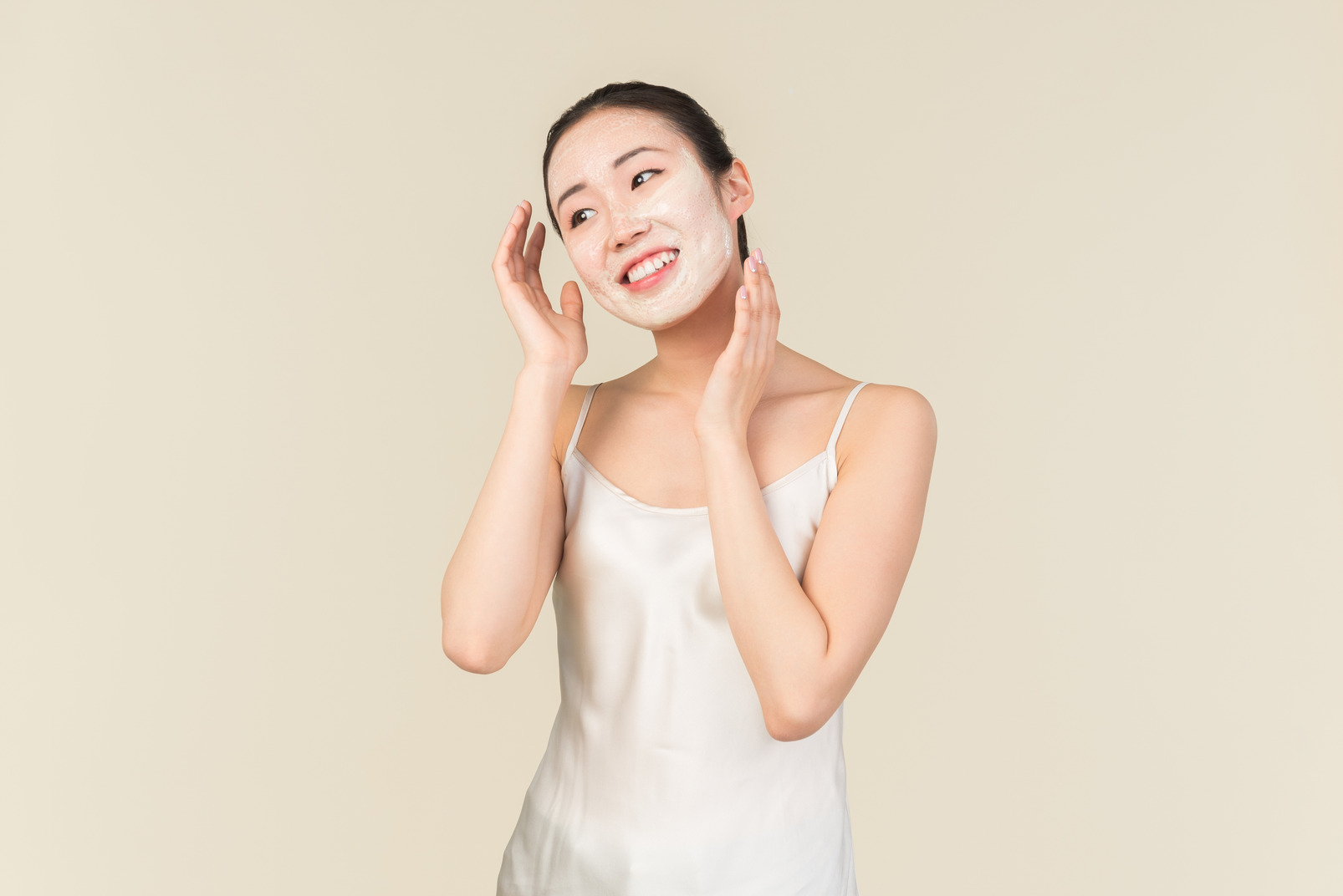 Relaxed young asian woman with facial mask touching head
