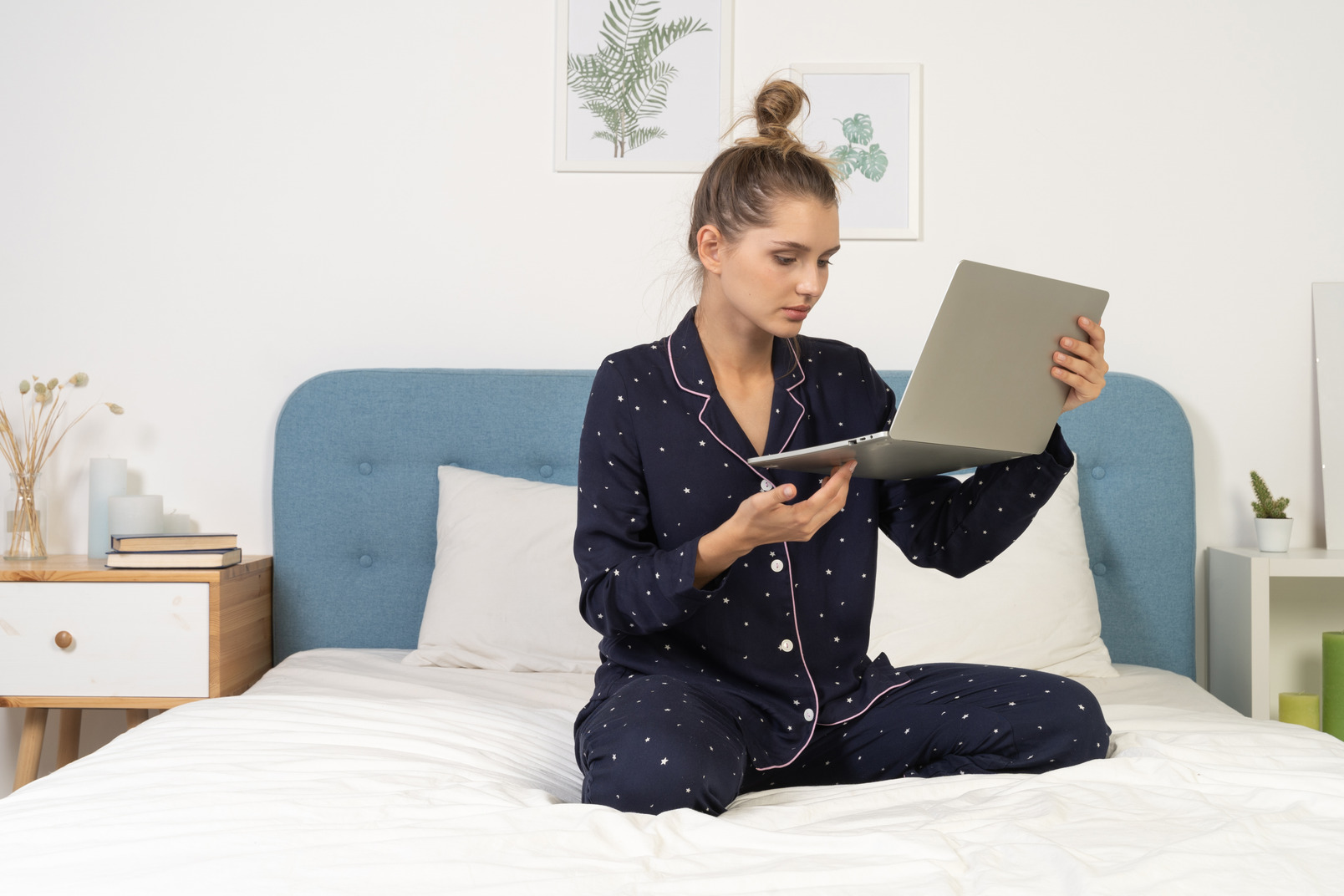 Front view of a young female sitting in bed with her laptop