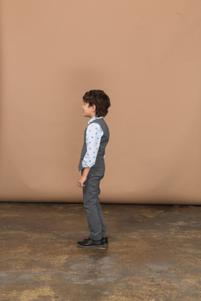 Boy in grey suit standing in profile