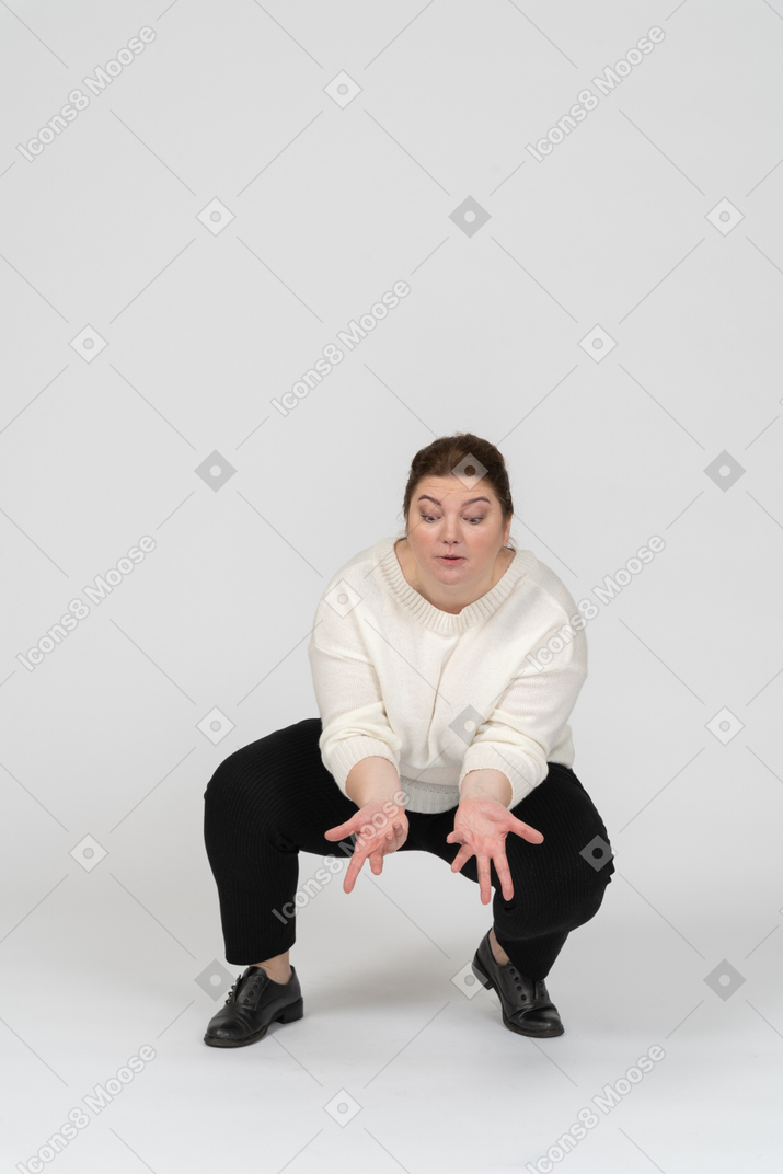 Front view of a plump woman in casual clothes squatting