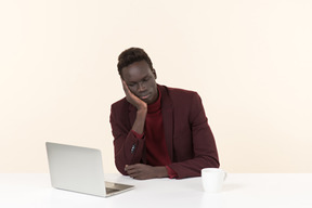 Eleganter schwarzer mann, der am tisch im büro sitzt