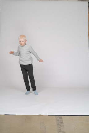 Front view of a standing boy looking down at something