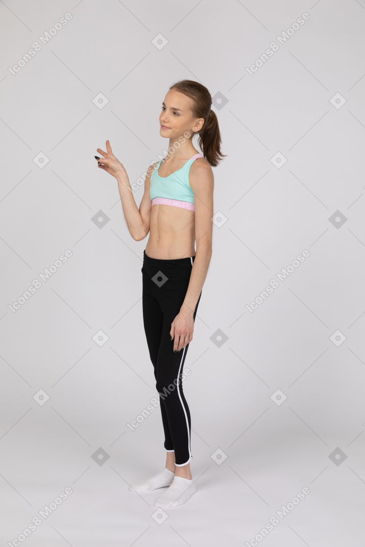 Una jovencita en ropa deportiva haciendo el signo de la paz.