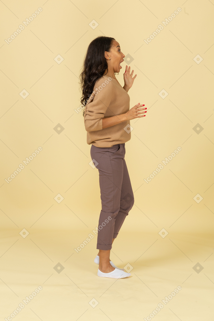 Vista lateral de una mujer joven asustada de piel oscura extendiendo sus dedos