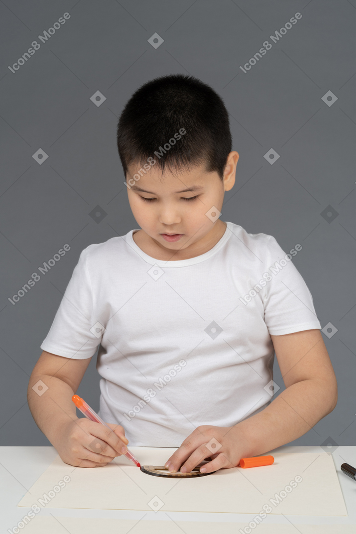 Asian boy drawing geometric shapes using ruler