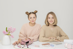 Dos amigas sentadas en la mesa desorganizada.