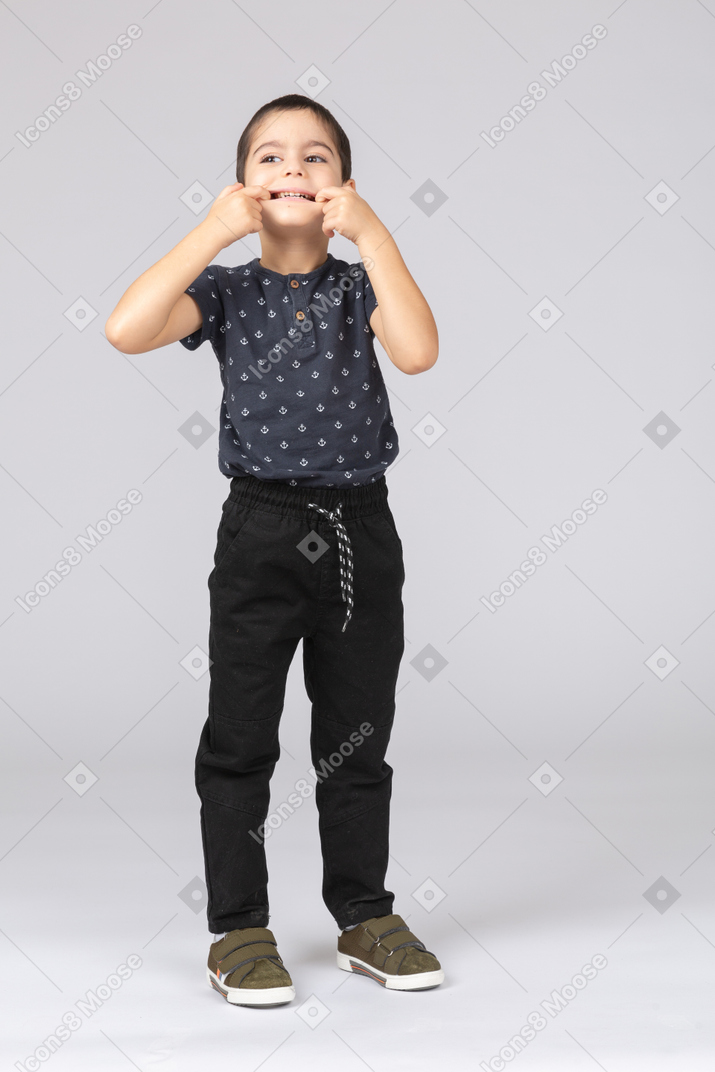 Front view of a cute boy opening mouth with fingers
