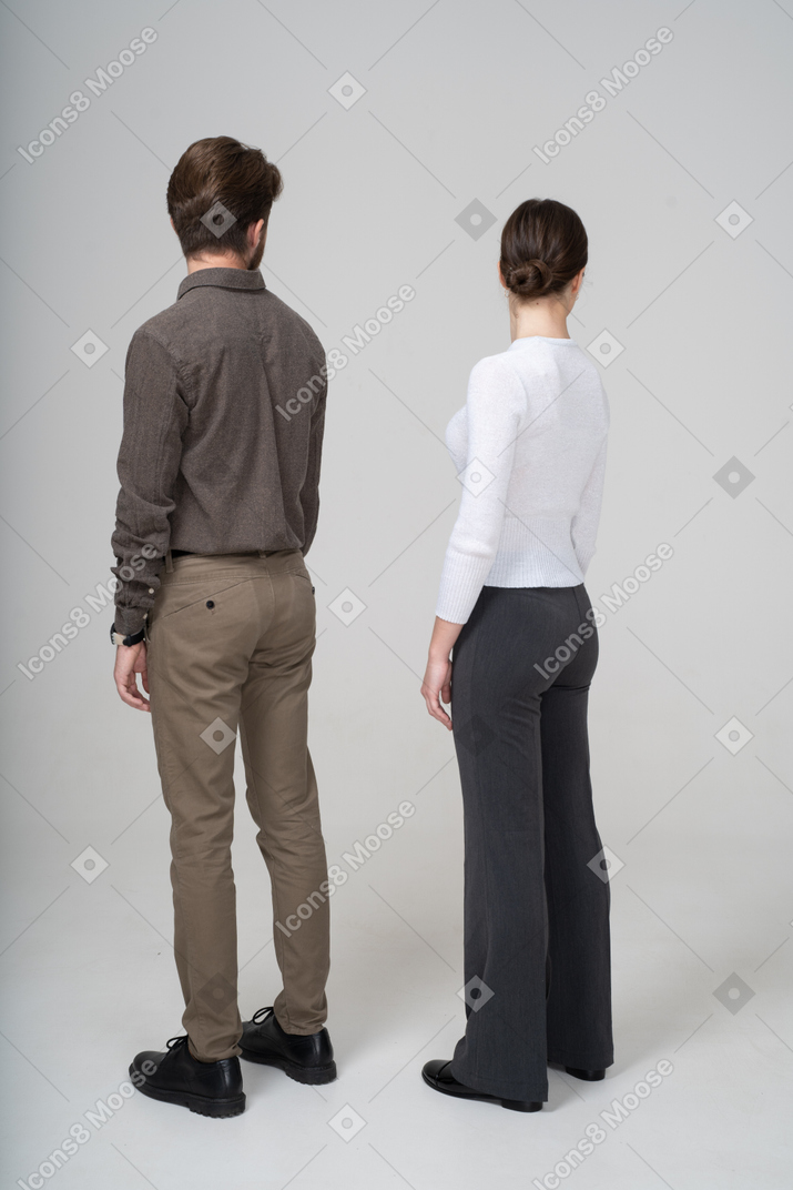 オフィスの服を着た若いカップルの4分の3の背面図
