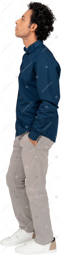 Seitenansicht eines mannes in freizeitkleidung, der mit den händen in den taschen steht