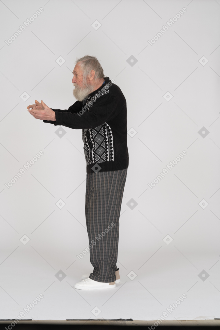Side view of an old man pointing with his hands to the left