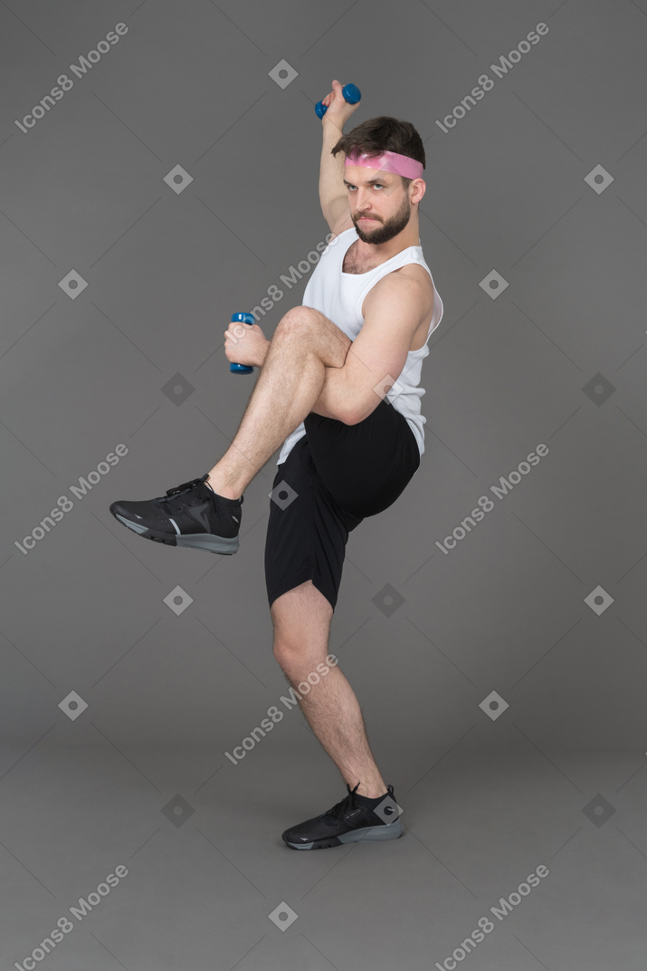 Expressive young man exercising with dumbbells