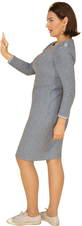 Vue latérale d'une femme en robe grise montrant un signe ok