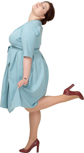 Side view of a woman in blue dress standing on one leg