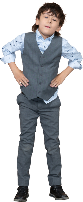 Front view of a boy in suit posing with hands on hips and looking at camera