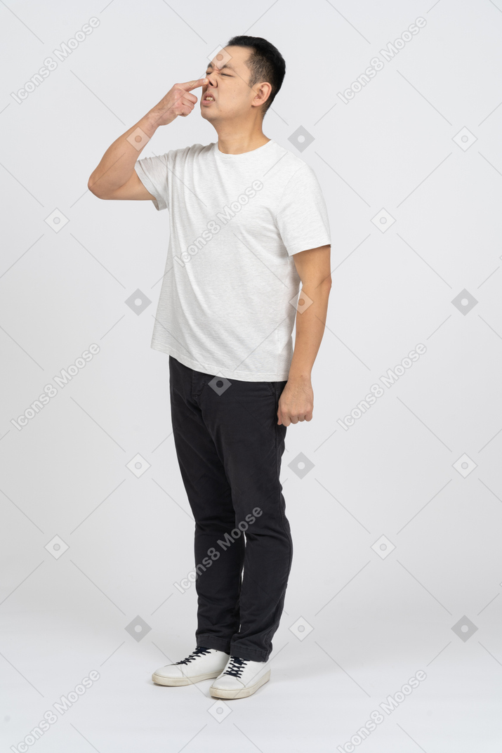 Three-quarter view of a man in casual clothes touching his nose