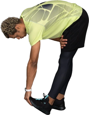 Side view of a dark-skinned young man bending down and touching his toes