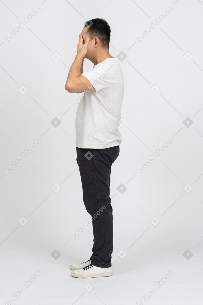 Seitenansicht eines mannes in freizeitkleidung, der die augen mit den händen bedeckt