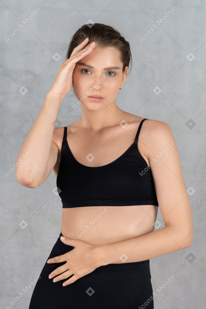 Portrait of a young woman touching her face & stomach