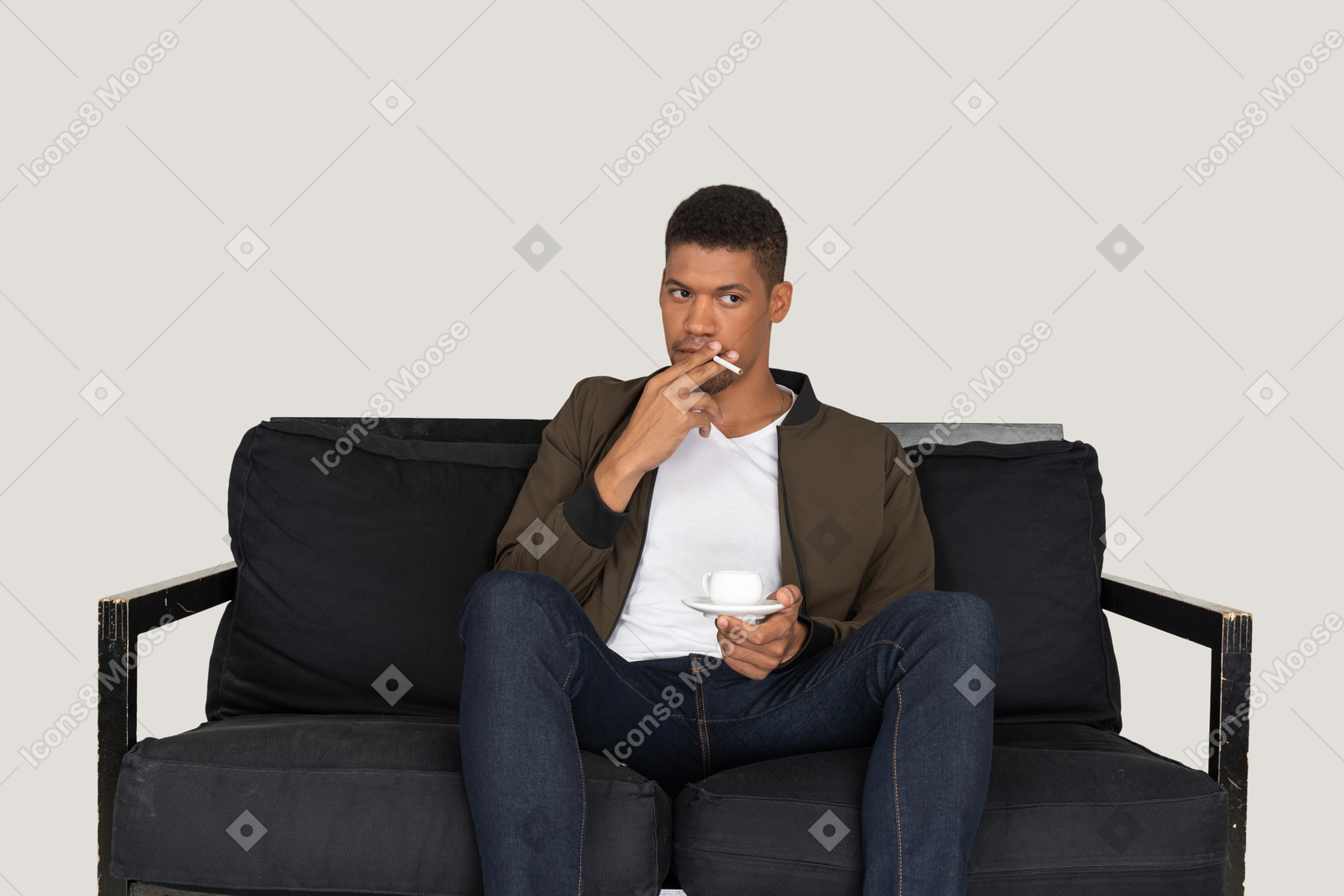 Vista frontal de um jovem sentado em um sofá segurando um cigarro e uma xícara de café