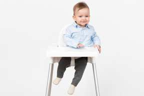 Adorable bebé niño sentado en una silla alta