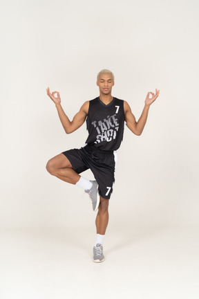 Vista frontal de un joven jugador de baloncesto meditando