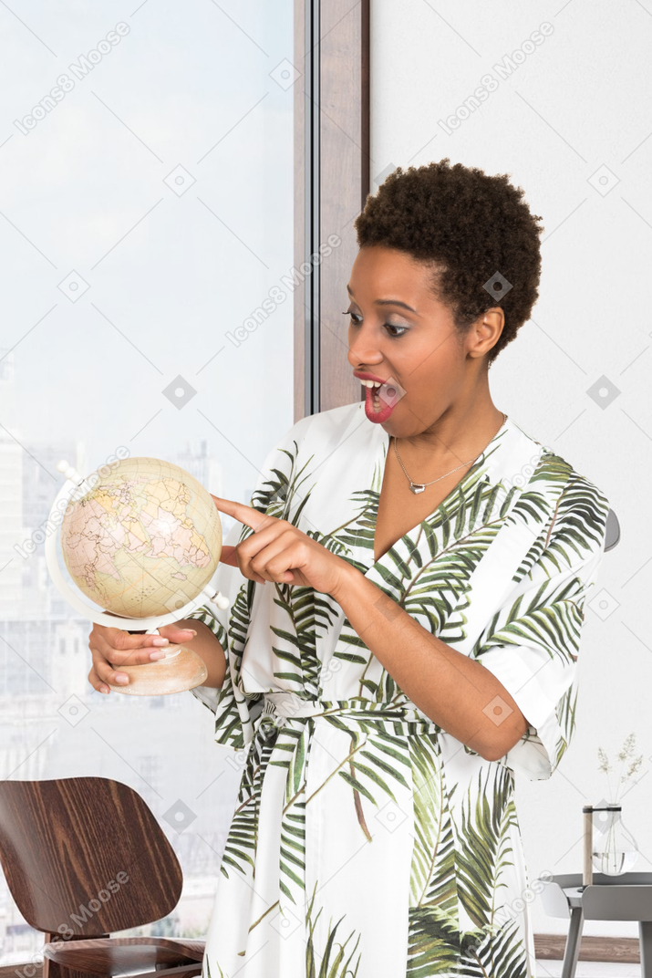 Excited young woman looking at her desk globe