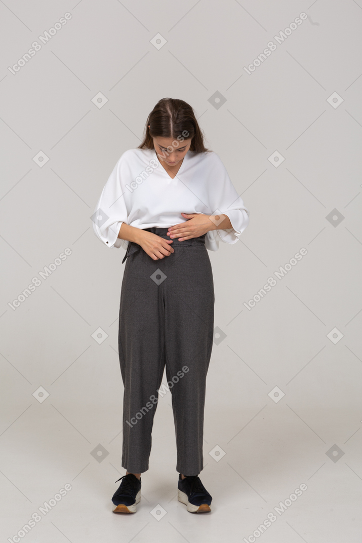 Vista frontal de uma jovem com roupa de escritório ajustando as calças
