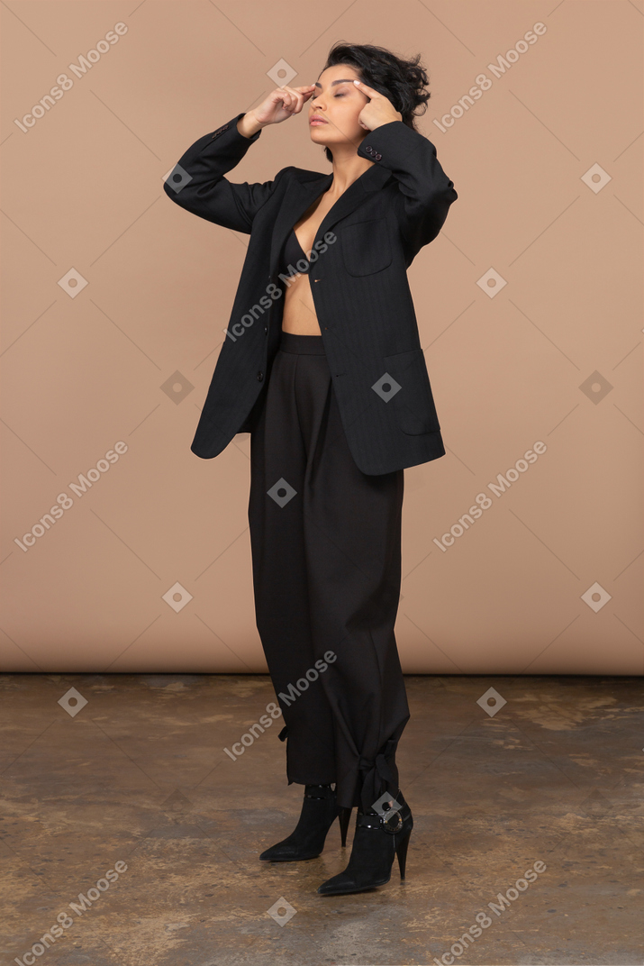 Three-quarter view of a tired businesswoman pointing fingers to her head