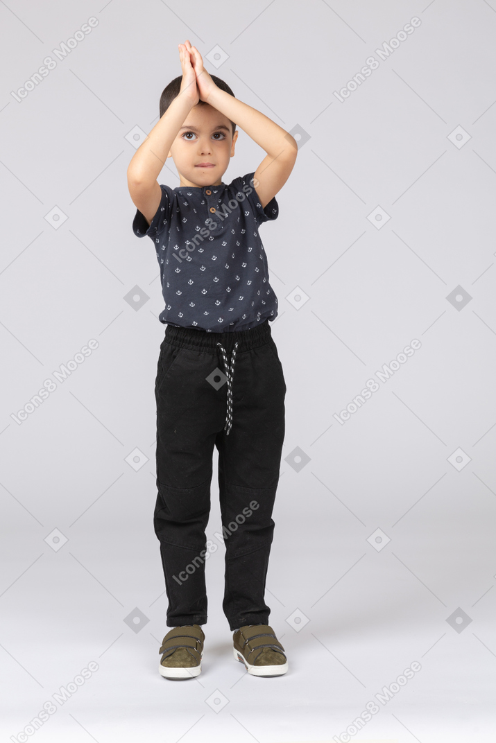 Front view of a cute boy posing with hands above head