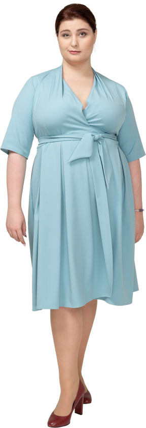 Вид спереди женщины в голубом платье, смотрящей в камеру