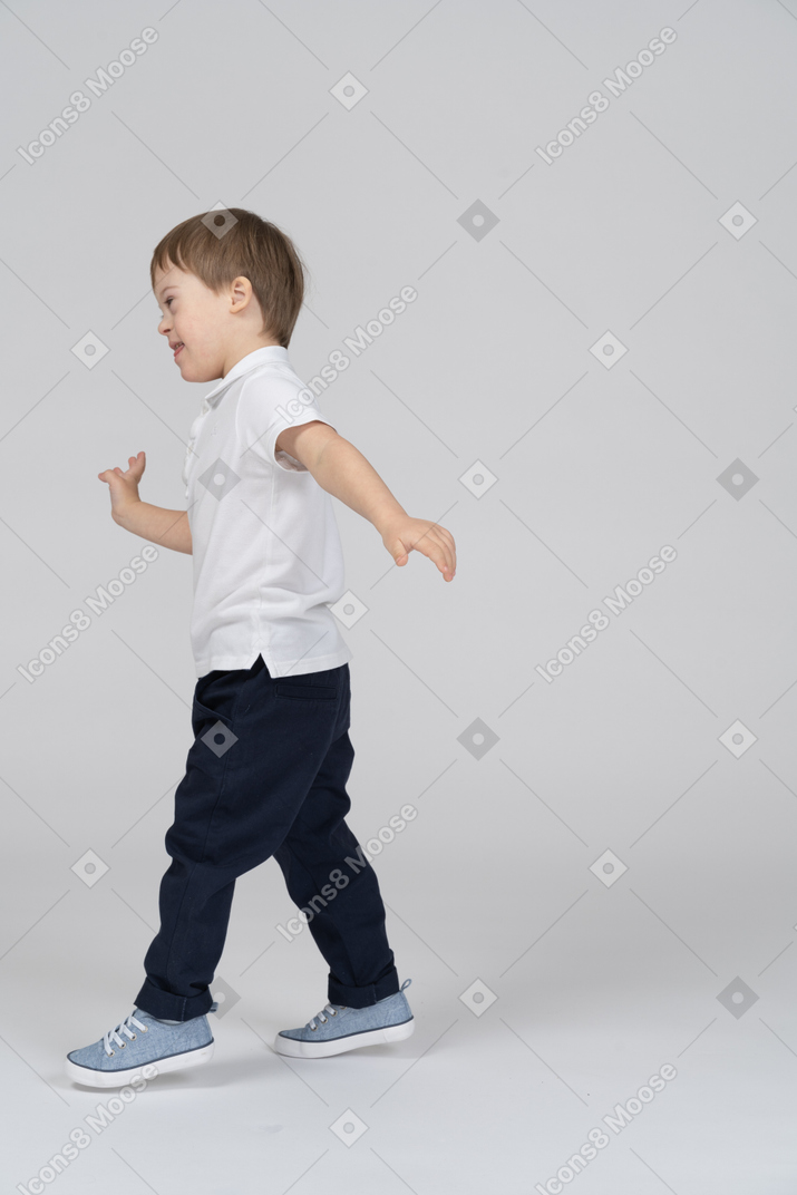 一个微笑的小男孩走路的侧视图
