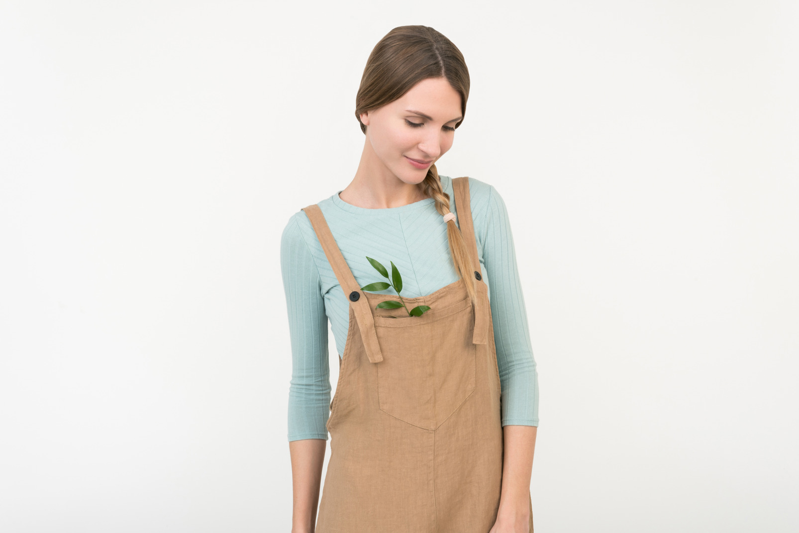 Young female farmer standing with green twig in her overalls