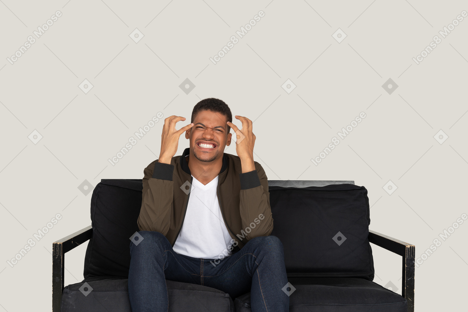Mad looking young man sitting on the sofa and touching his head with hands