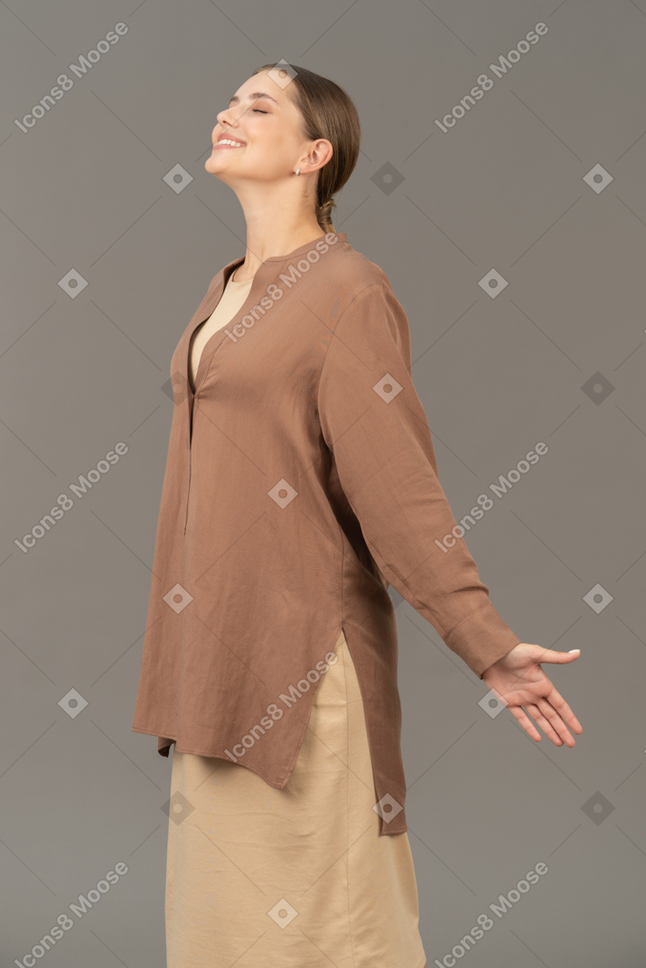 Vista lateral de uma mulher sorridente com os olhos fechados e braços abertos