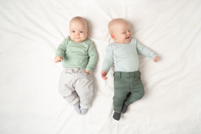 赤ちゃんの双子が隣同士に横になっています。