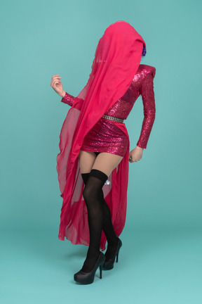 Drag queen in pink drace covering face with long skirt