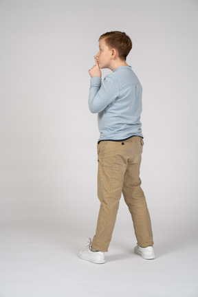 Side view of a boy making shhh gesture