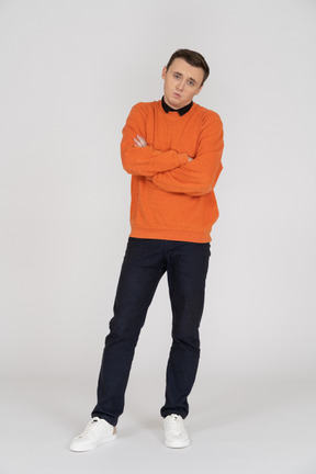 Junger mann im orangefarbenen sweatshirt stehend