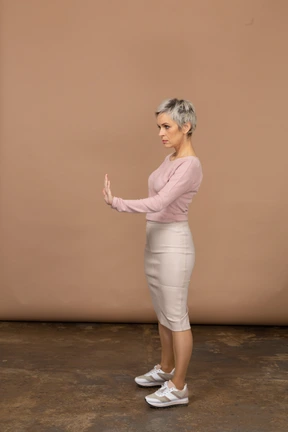 Side view of a woman in casual clothes showing stop gesture